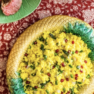 A plate of yellow rice and meat on a table.