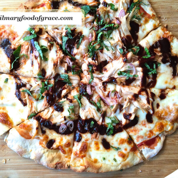 A pizza with sauce and onions on a wooden surface.