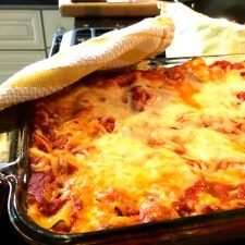 A traditional beef and cheese lasagna in a baking dish on the stove.