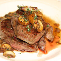 A steak with mushrooms and sauce on a plate, perfect for a recipe.